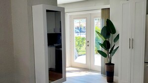 Ein geräumiges Zimmer mit einer großen Schiebetür zu einem Außenbereich, weißen Schränken und einem Blumentopf.