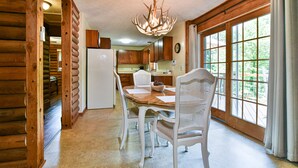 A wooden cabin interior with a dining table, chairs, a chandelier, and large windows. - Rustic Cabin in the Woods Star5vacations (Black Mountain)