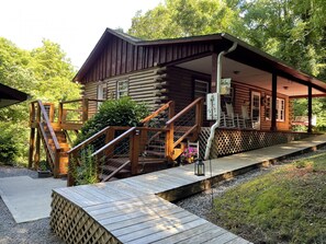 A wooden cabin with a porch, wooden stairs, and a small deck.