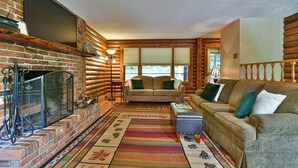 A log cabin interior with a fireplace, wooden walls, a sofa, and a patterned rug. - Rustic Cabin in the Woods Star5vacations (Black Mountain)