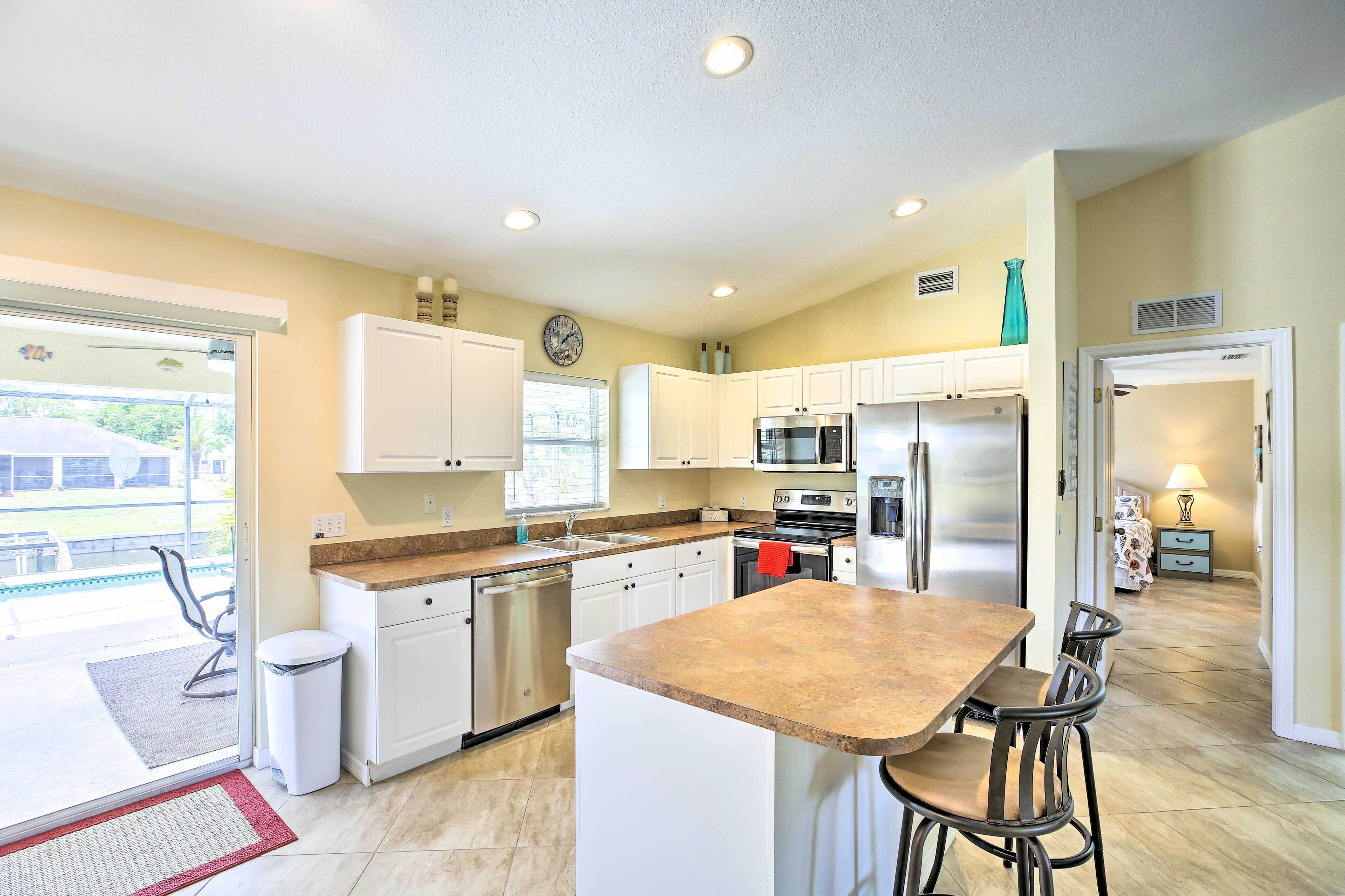 A modern kitchen with white cabinets, stainless steel appliances, and a large island with bar stools.