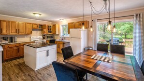 Une cuisine avec des meubles de rangement en bois, un réfrigérateur blanc et un coin repas comprenant une table et des chaises en bois.