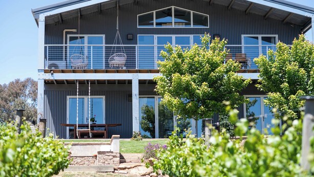 A two-story building with a balcony, a swing, and a stone pathway leading to a wooden bench. - Mortimer's Wines Loft - Adults Only Retreat (Orange)
