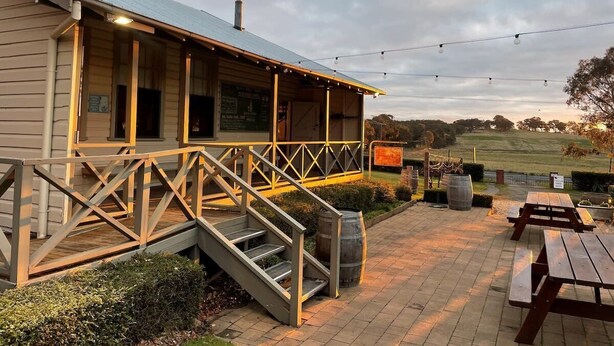 Een houten gebouw met een veranda, buitenmeubels en uitzicht op het landschap.