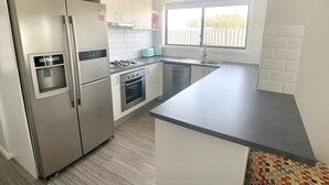 A modern kitchen with stainless steel appliances, a built-in oven, and a large window providing natural light.