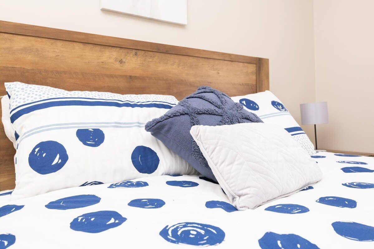 Un lit avec une couvre-lit à pois blancs et bleus, une tête de lit en bois et deux oreillers à pois bleus.