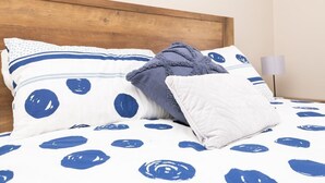 A bed with a white and blue polka dot bedspread, a wooden headboard, and two pillows with blue polka dots. - Kinross on Cox • Cosy Retreat • Opposite KWS (Orange)