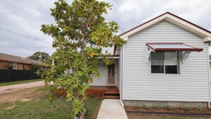 A single-story house with a front porch, a small window, and a red roof. - Kinross on Cox • Cosy Retreat • Opposite KWS (Orange)