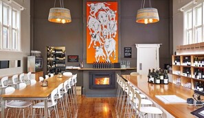A bar area with a fireplace, white chairs, and a wine display.