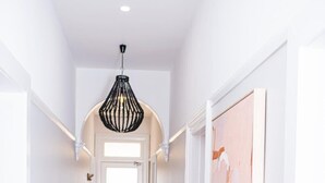 En gang med trægulv, hvide vægge, en bænk og en hængende lampe.