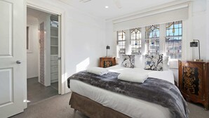 A bedroom with a bed, a wardrobe, a nightstand, and a window with a view.