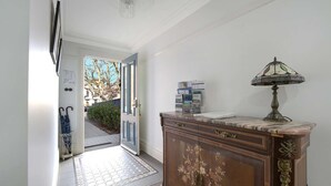 A hallway with a wooden cabinet, a lamp, and a door leading outside.