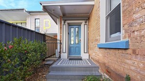 A residential building with a blue front door, a small porch, and a brick exterior.