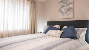 Quarto com cama, cortinas e uma obra de arte na parede.