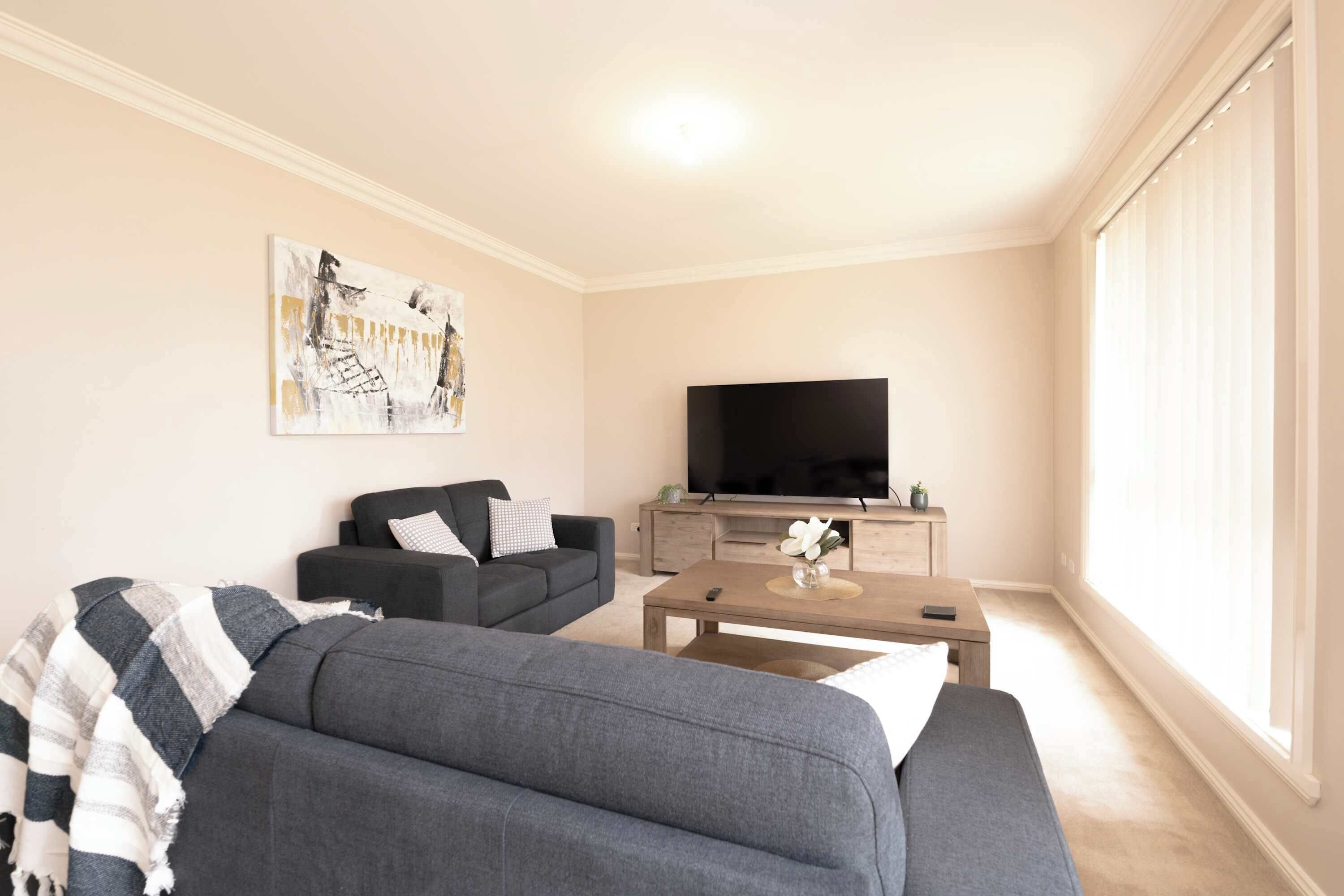 Ein Wohnzimmer mit einer Couch, einem Couchtisch, einem Fernseher und einem Gemälde an der Wand.