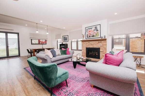 A spacious living room with a fireplace, a dining area, and a large window.