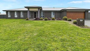 A two-story brick house with a garage, a front porch, and a well-maintained lawn. - Emmaville - Modern, Convenient & Pets Allowed (Orange)