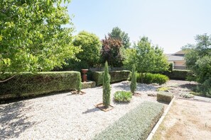 A well-maintained garden with neatly trimmed hedges, a gravel path, and various shrubs.