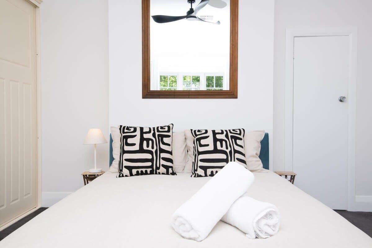 A neatly made bed with two pillows, a bedside lamp, and a ceiling fan.