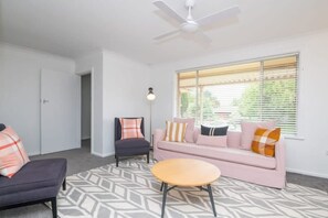 A living room with a ceiling fan, a sofa set, a coffee table, and a patterned rug.