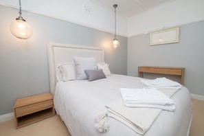 A neatly arranged bedroom with a large bed, bedside tables, and hanging light fixtures.