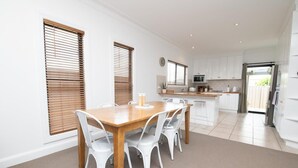 Una cocina moderna con armarios blancos, una mesa de comedor de madera y sillas blancas.