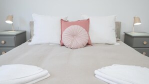 Una cama con dos mesitas de noche, cada una con una lámpara, y un arreglo de almohadas.