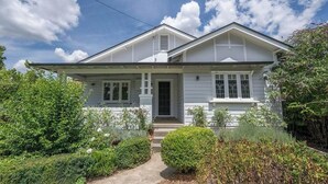 A single-story house with a front porch, a chimney, and a well-maintained garden. - Bindi Cottage | Classic Charm, Short Stroll to CBD (Orange)