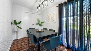 Una sala de conferències amb una taula fosca, cadires blaves, una planta en test i una làmpada penjant.