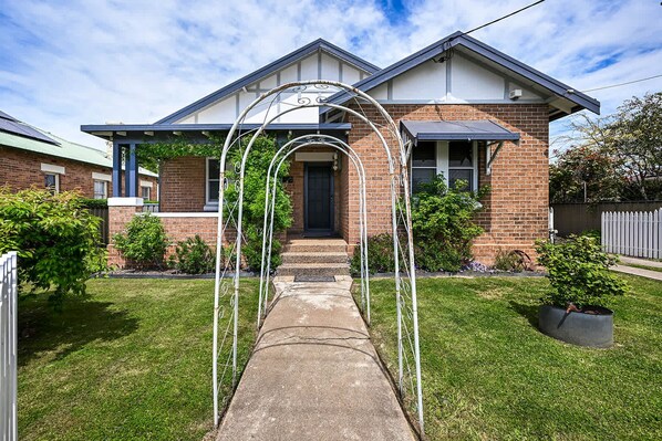 A residential house with a brick facade, a front porch, and a clear sky.