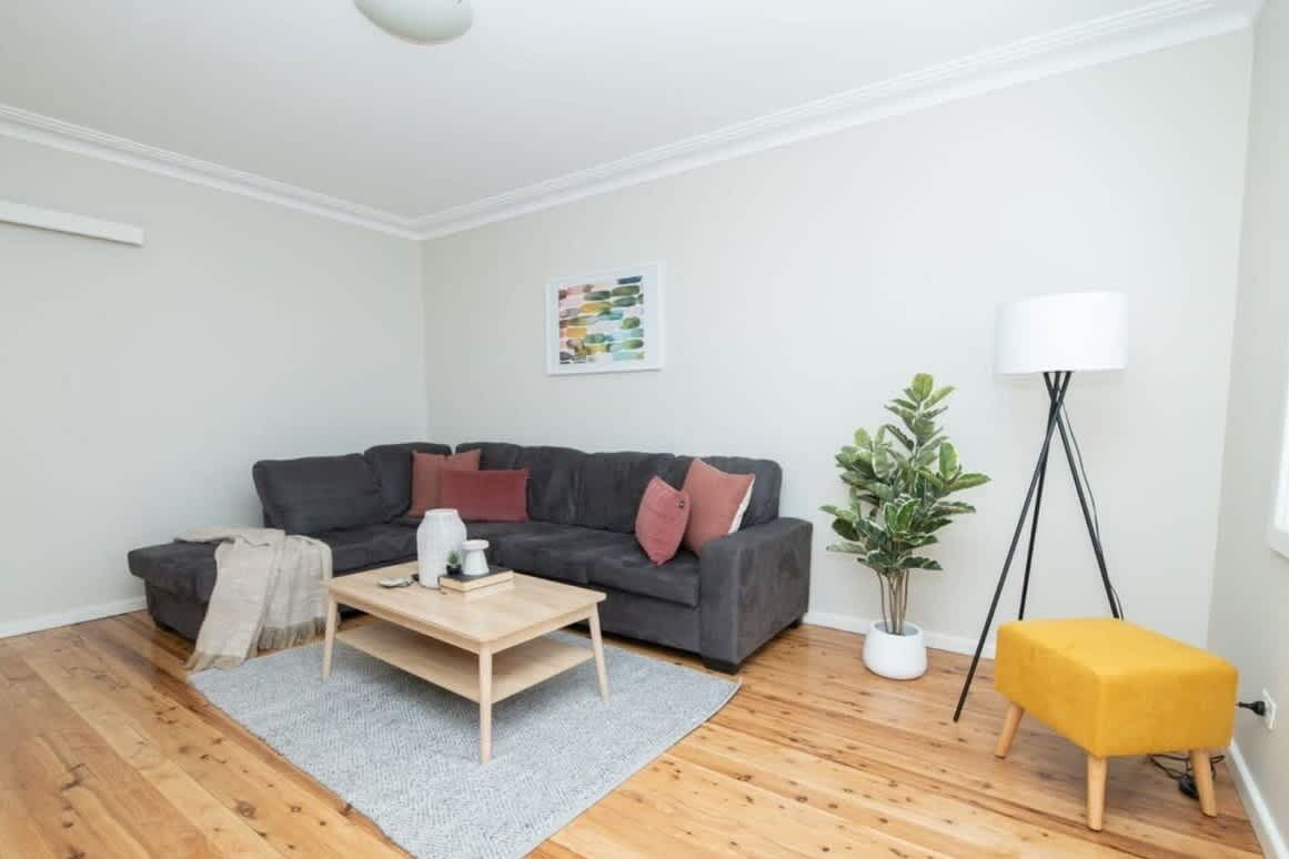 A living room with a grey sofa, a wooden coffee table, a floor lamp, and a potted plant.