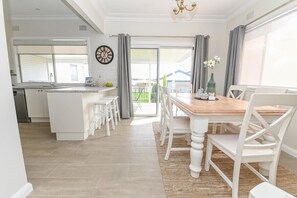 Eine moderne Küche mit weißen Schränken, einem Holztisch und Blick ins Freie.