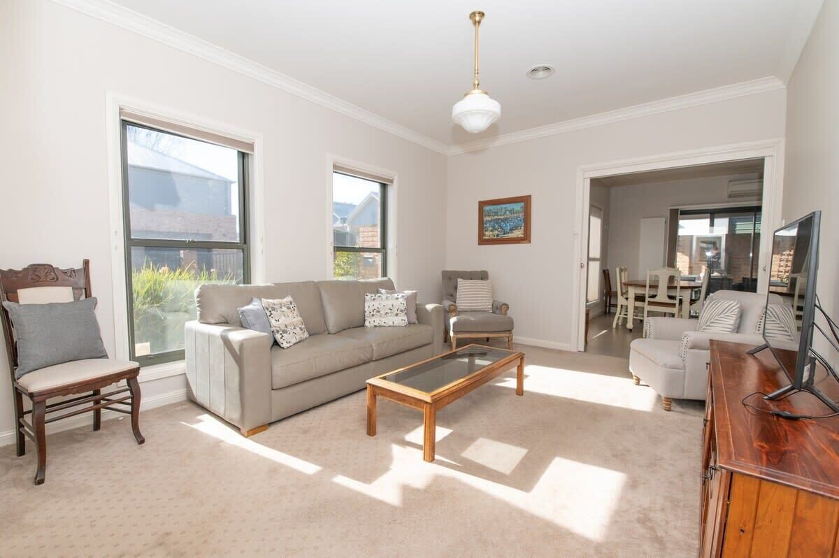 A living room with a sofa, armchairs, a coffee table, and a TV stand.
