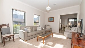 Una sala de estar con sofá, sillones, una mesa de centro y un mueble para televisión.