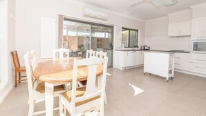 Una cocina moderna con armarios blancos, una mesa de comedor de madera y un ventilador de techo.
