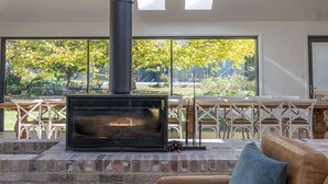 A modern interior with a fireplace, skylights, and a view of greenery.