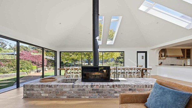 A modern living room with a fireplace, large windows, and a view of the garden.