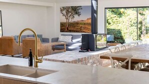 A modern kitchen with a skylight, a fireplace, and a dining area with a view of the outdoors.