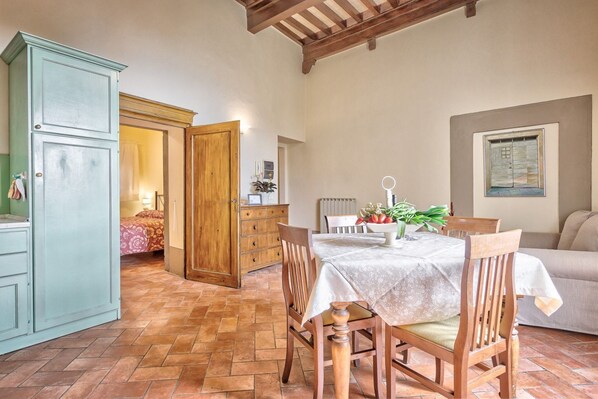 A dining area with a table set for two, wooden chairs, a cabinet, and a door leading to another room.