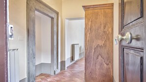 Un pasillo con un radiador, una puerta de madera y una pared blanca.
