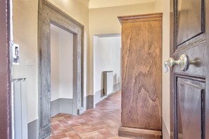 Ein Flur mit Heizkörper, Holztür und weißer Wand.