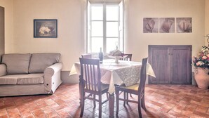 Un comedor con una mesa, sillas, un sofá, un ventanal y decoración en la pared.