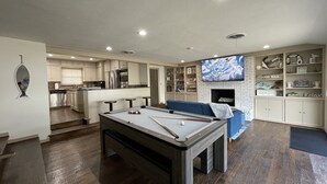 Een moderne woonkamer met een pooltafel, een televisie en een open haard.