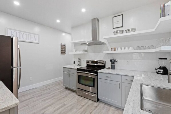 A modern kitchen with stainless steel appliances, white cabinetry, and a built-in oven.