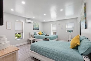 Une chambre avec deux lits, une petite table, une chaise et une fenêtre.