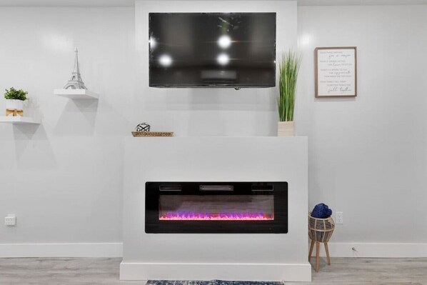 Un salon moderne avec un téléviseur à écran plat fixé au-dessus d’une cheminée.