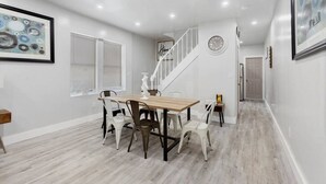 Ein Essbereich mit Holztisch und Stühlen, einer Treppe und einer Uhr an der Wand.