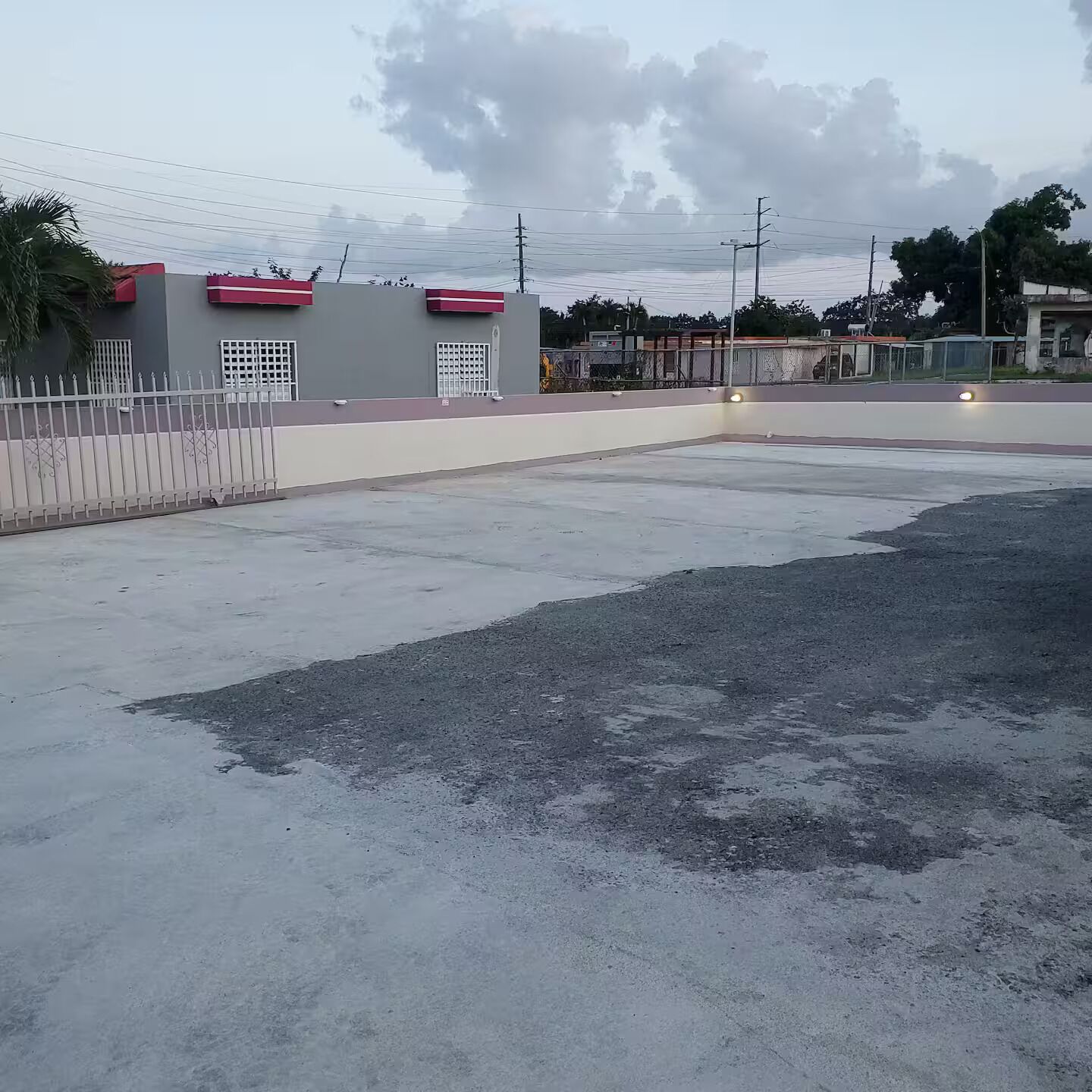 A large, open parking area with a concrete surface and a fence on one side.
