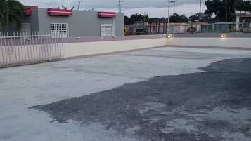 A large, open parking area with a concrete surface and a fence on one side.