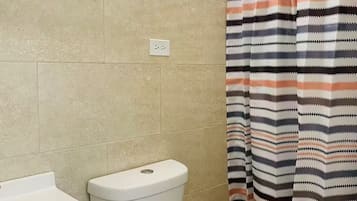 Une salle de bain équipée de toilettes, d’un lavabo et d’un rideau de douche.